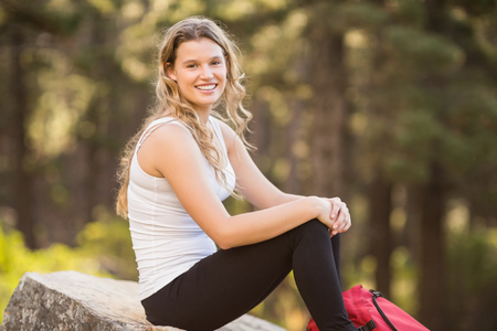 Young happy jogger sitting on rock and looking at camera in the natureの写真素材