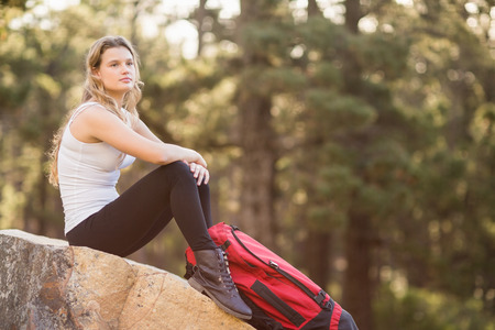 Young jogger sitting on rock and looking away in the natureの写真素材