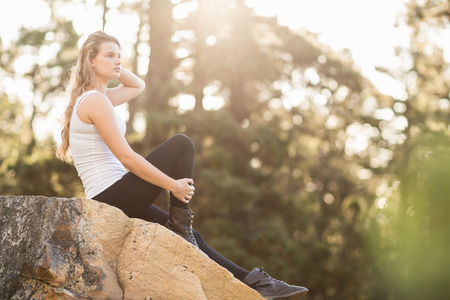 Young jogger sitting on rock and looking away in the natureの写真素材