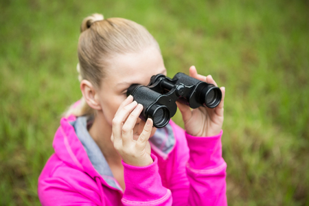 Upward view of a female hiker looking through the binocularsの写真素材