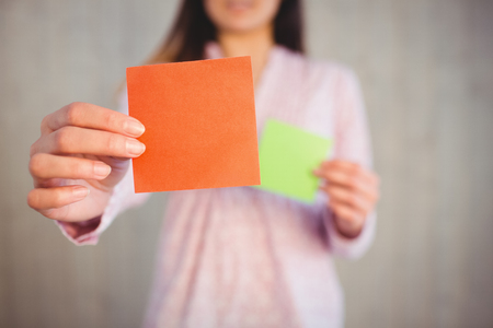 Woman holding green and orange cards on wooden planks backgroundの写真素材
