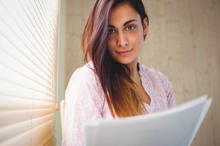 Pretty brunette reading documents beside window in a bright roomの写真素材