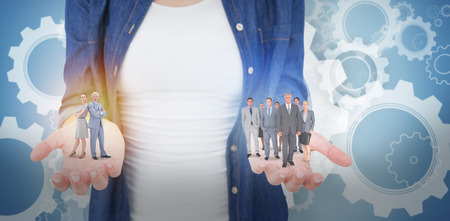 Serious businessman standing back to back with a woman  against white wheels and cogs on blueの写真素材