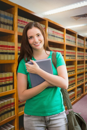 Student using her tablet in library against close up of a bookshelfの写真素材