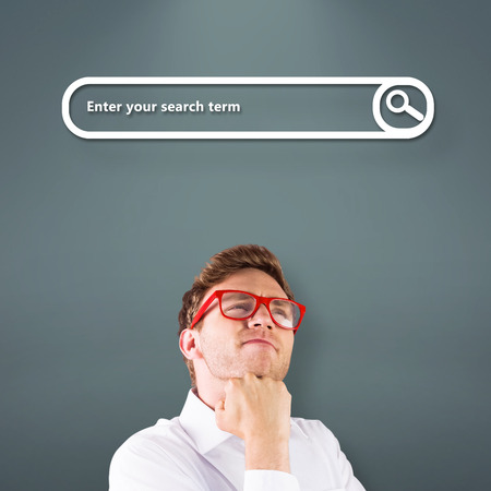 Young geeky businessman with hand on chin against grey vignetteの写真素材