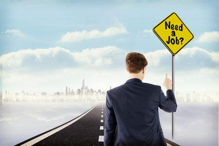 Businessman pointing something with his finger against yellow sign by roadの写真素材