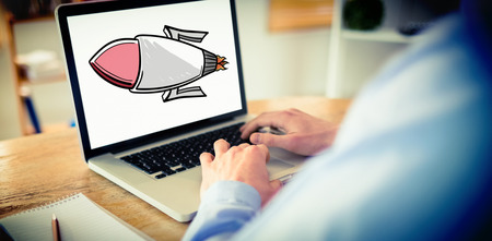 Businessman working on his laptop against rocketの写真素材