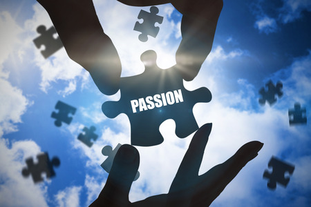 The word passion  and hands holding jigsaw against bright blue sky with cloudsの写真素材