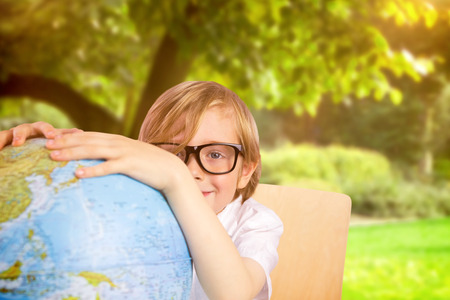 Cute pupil holding globe against trees and meadow in the parkの写真素材