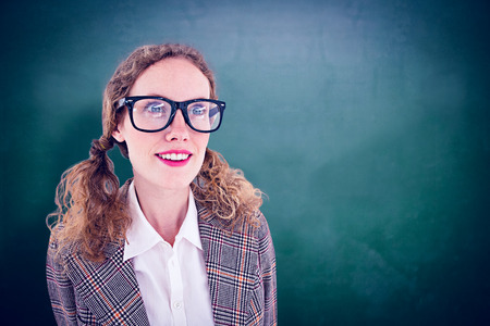 smiling  geeky hipster girl looking at something against green chalkboardの写真素材
