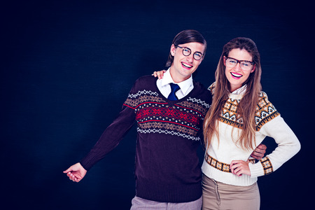Happy geeky hipster couple embracing against blackboardの写真素材