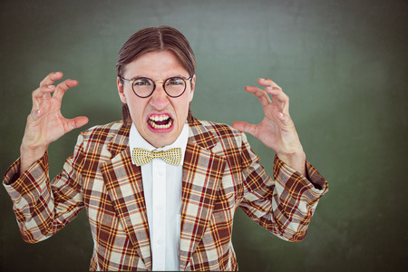 Furious geeky hipster looking at camera against green chalkboardの写真素材