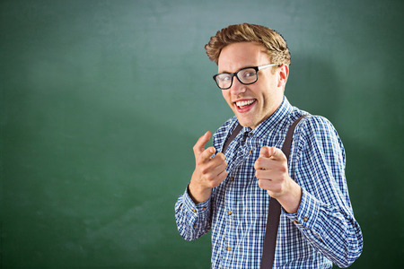 Geeky hipster pointing at camera against green chalkboardの写真素材