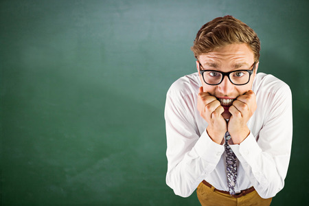 Young geeky businessman biting his nails against green chalkboardの写真素材