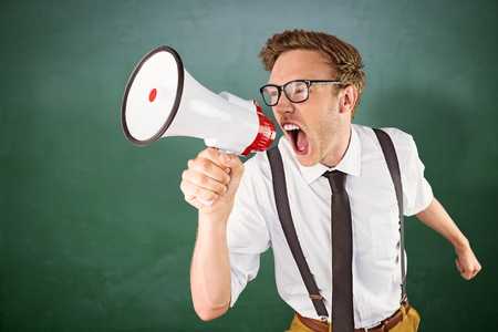 Geeky businessman shouting through megaphone against green chalkboardの写真素材