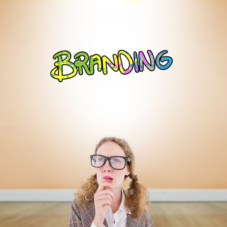 Geeky hipster woman thinking with hand on chin against room with wooden floorの写真素材
