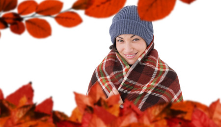 Smiling brunette with checked blanket against autumn leaves