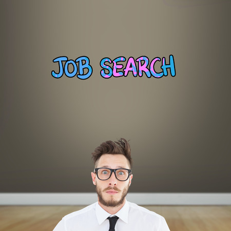 Geeky young businessman looking at camera against room with wooden floorの写真素材