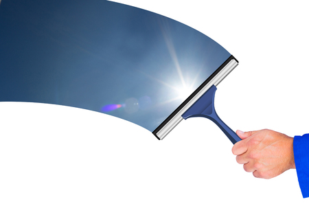 Hand using wiper against blue sky with clouds