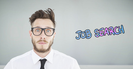 Geeky young businessman looking at camera against room with wooden floorの写真素材