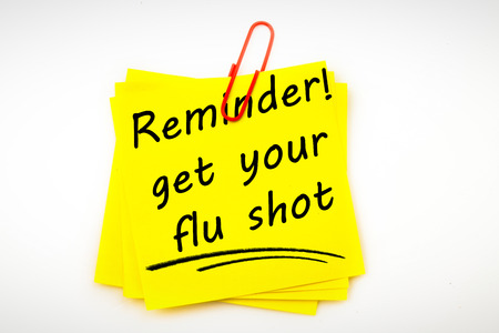 Flu shot reminder against sticky note with red paperclipの写真素材