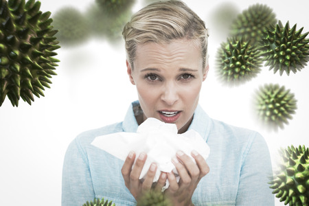 Blonde sick woman holding lots of tissues against virusの写真素材