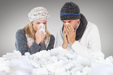 Couple sneezing in tissue against grey vignetteの写真素材