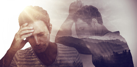 Upset man leaning on white background against trees and mountain range against cloudy skyの写真素材