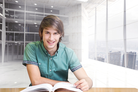 Student sitting in library reading  against modern room overlooking cityの写真素材