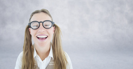 Female geeky hipster smiling at camera against grey wallの写真素材
