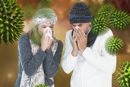 Couple sneezing in tissue against autumn sceneの写真素材