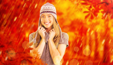 Happy blonde in winter clothes posing against autumn sceneの写真素材