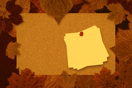 Sticky note with red pushpin against autumn leaves patternの写真素材