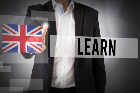 The word learn and businessman standing and pointing against abstract grey roomの写真素材