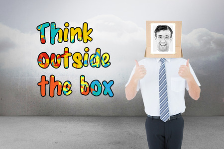 Businessman with photo box on head against clouds in a roomの写真素材