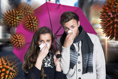 Couple blowing nose while holding umbrella against blurry new york streetの写真素材