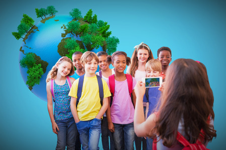 Cute pupils using mobile phone  against blue background with vignetteの写真素材