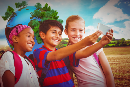 Happy kids taking selfie in school corridor against blue sky over fieldsの写真素材