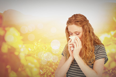 Sick blonde woman blowing her nose against autumn sceneの写真素材
