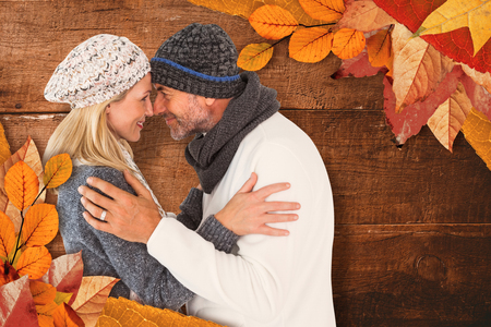 Smiling cute couple romancing over white background against overhead of wooden planksの写真素材