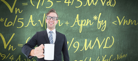 Happy geeky businessman holding coffee mug against green chalkboard