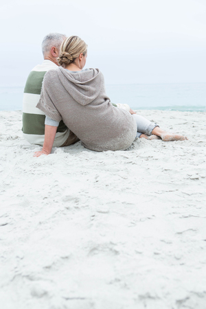 Cute couple sitting in the sand at the beachの写真素材