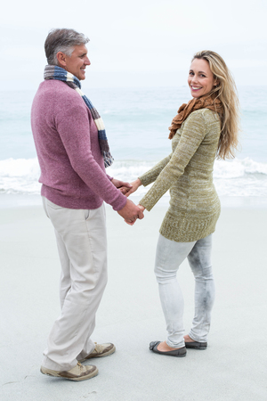 Happy couple standing holding each others hands at the beachの写真素材