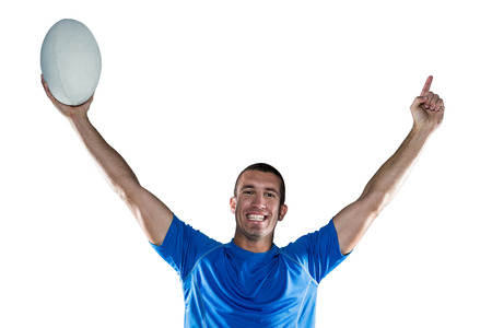 Portrait of rugby player in blue jersey holding ball with arms raised against white backgroundの写真素材