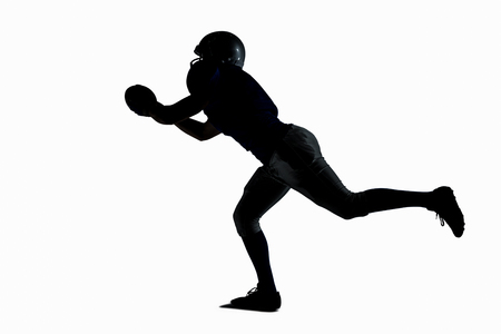 Silhouette American football player catching ball against white backgroundの写真素材