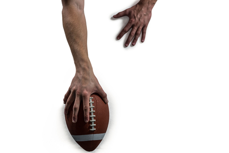 Cropped image of American football player holding ball against white backgroundの写真素材
