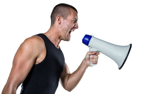 Irritated male trainer yelling through megaphone against white backgroundの写真素材