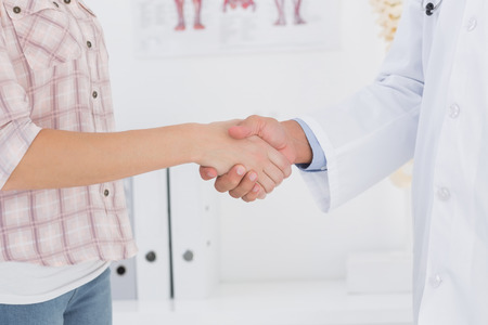 Patient shaking hands with doctor in medical officeの写真素材