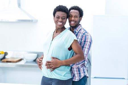 Portrait of man embracing his wife while standing in kitchenの写真素材