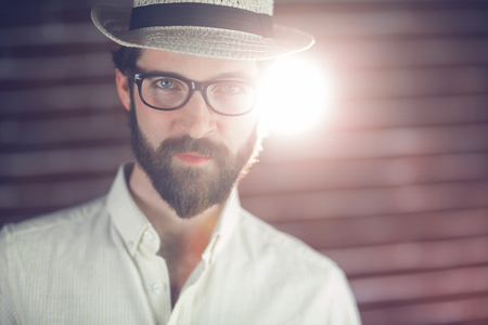 Portrait of confident man wearing hat and eyeglasses against wallの写真素材